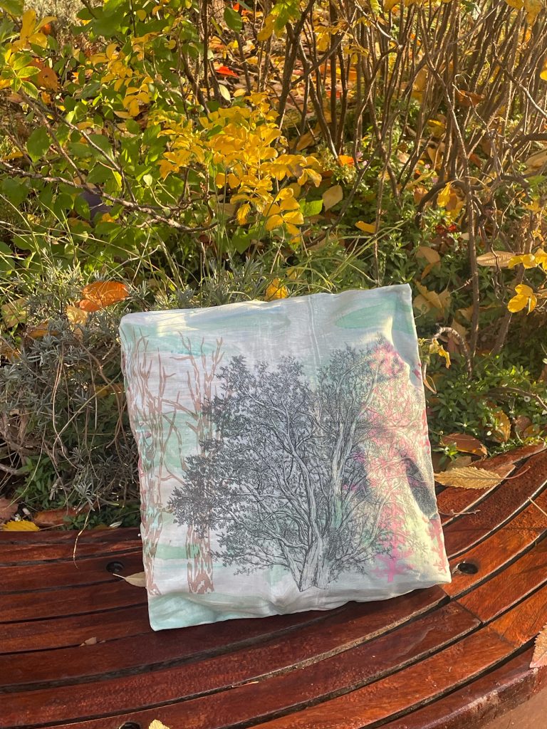 Fairytales a cushion with a printed leaf design, on a wooden bench