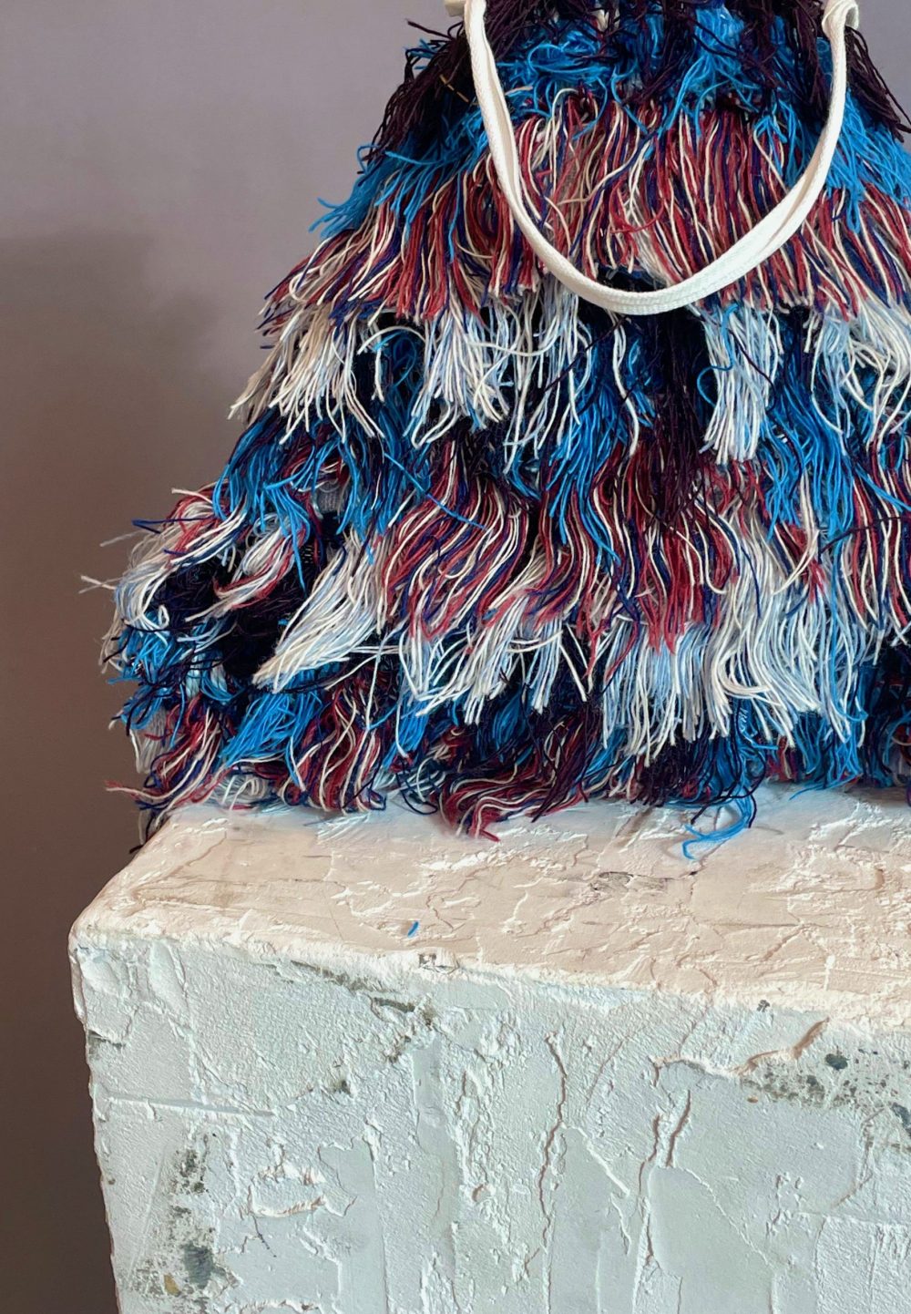 Living on the Water a bag made of fringed woven fabric, on a concrete block