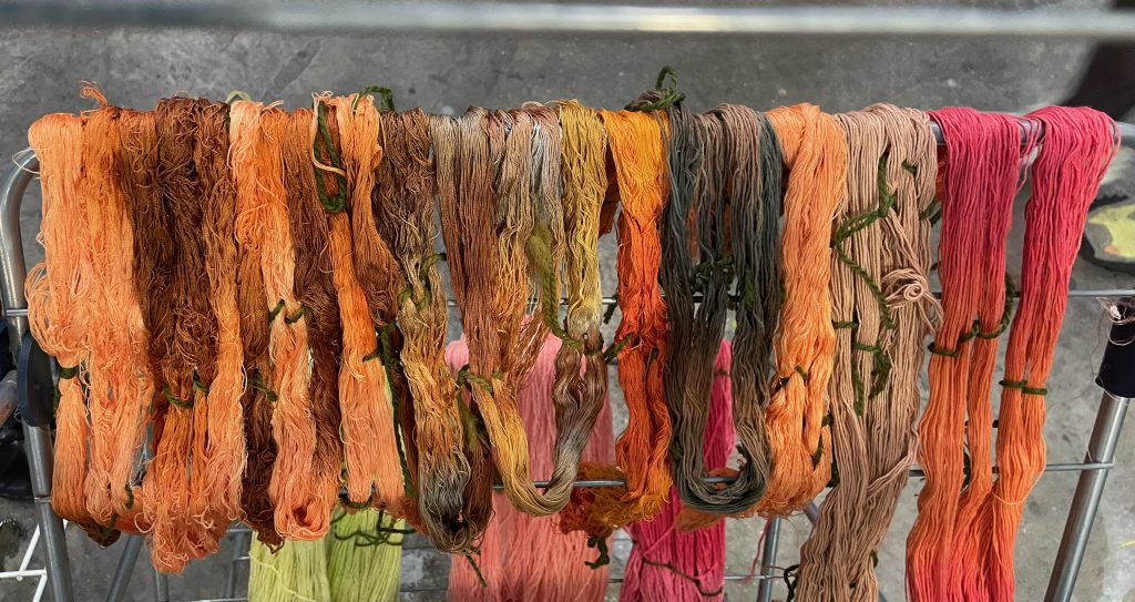 My process Dyed yarn in natural shades of red, orange and brown drying on a rack