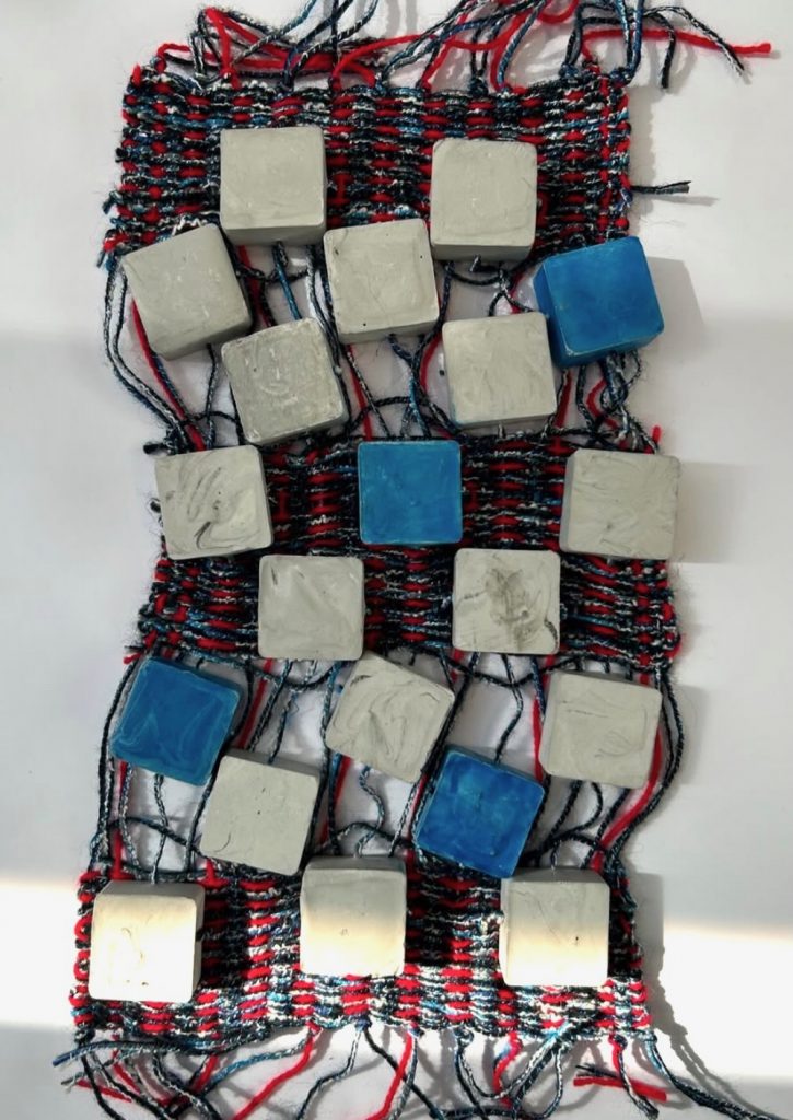 My process woven fabric in red and blue with square blocks of plaster incorporated